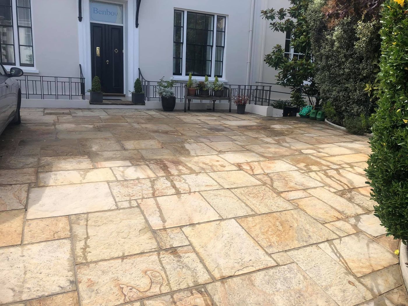 Patio and driveway after pressure washing: warm golden stone paving